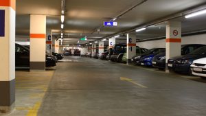 Underground parking garage with multiple parked cars, clean concrete floors, and clearly marked directional signs and pillars labeled "C -1".